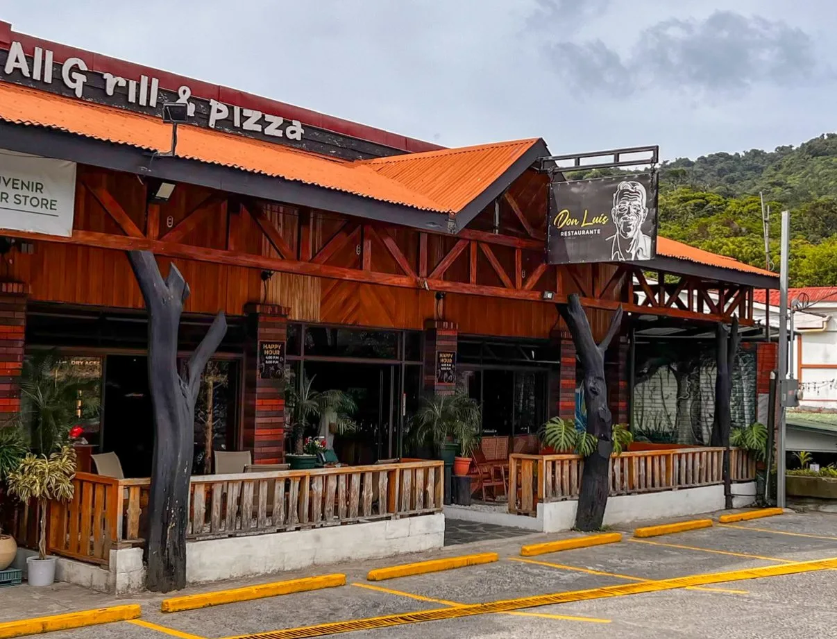 Fachada de Don Luis desde la calle, con el rótulo del rostro de Don Luis y el parqueo al frente