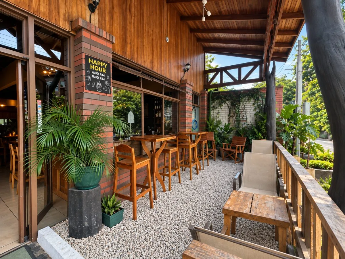 Terraza de Don Luis con mesas altas de madera, plantas y el rótulo del Happy Hour